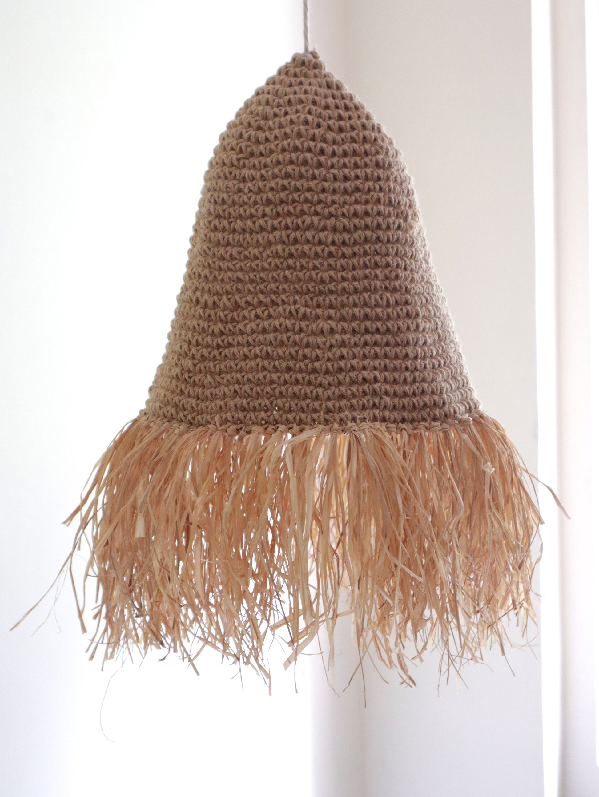 Jute crochet lampshade with feather details on a white background