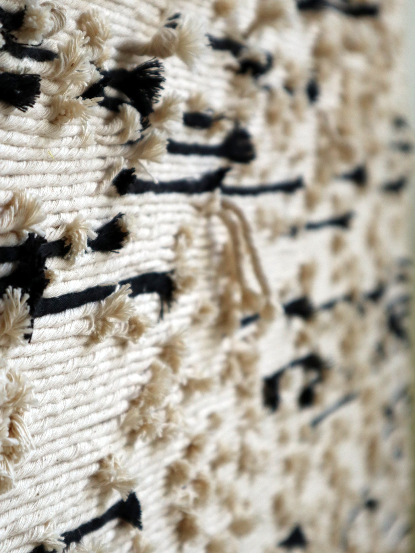 Close-up of a textured fabric wall art with black and white pattern